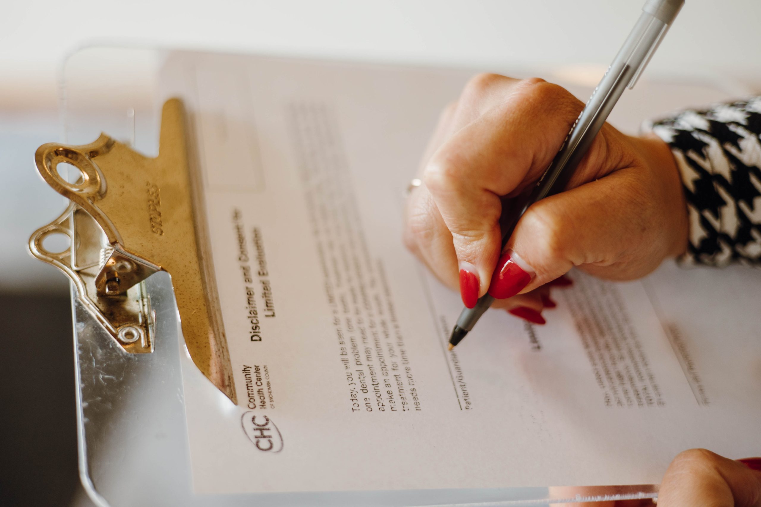 close up of a hand filling out a paper form on a clipboard